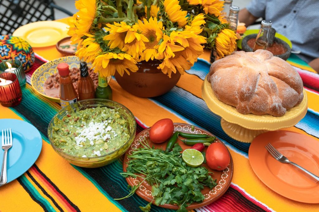 Colorful Mexican table with food, sunflowers, and traditional textiles.